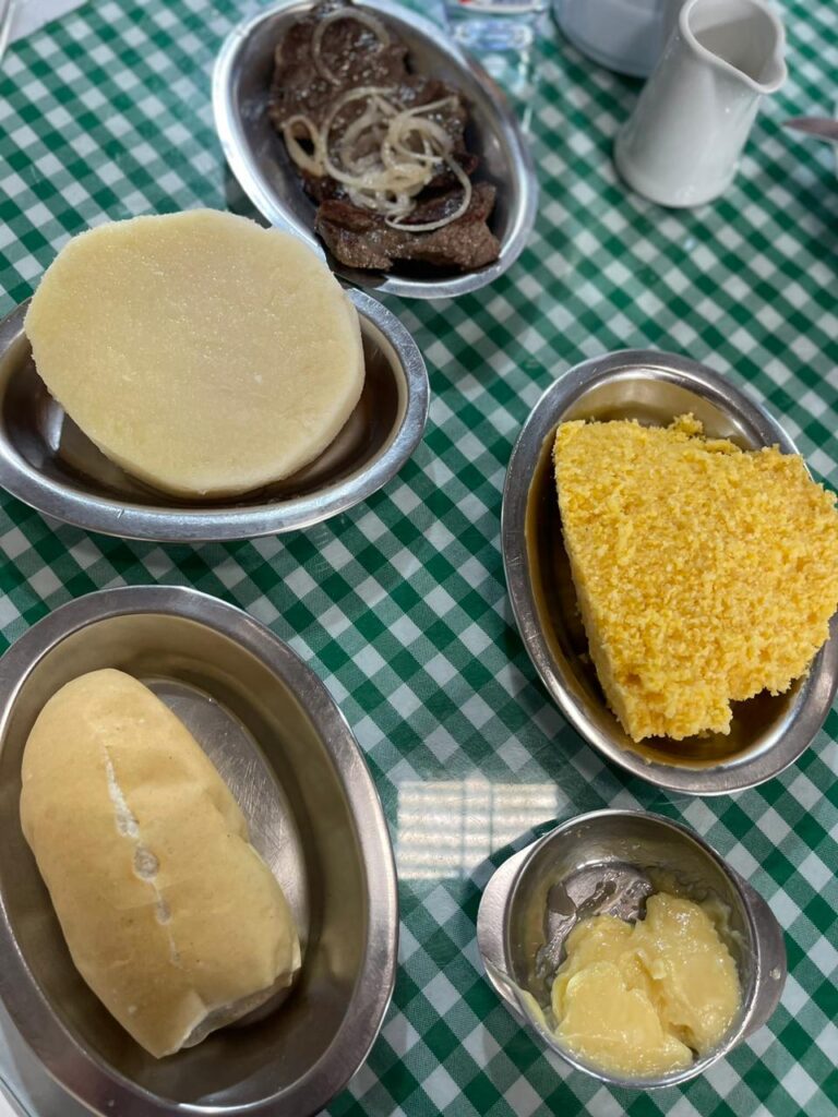 Café da manhã regional: inhame com carne de sol acebolada, cuscuz com leite e pão com manteiga.